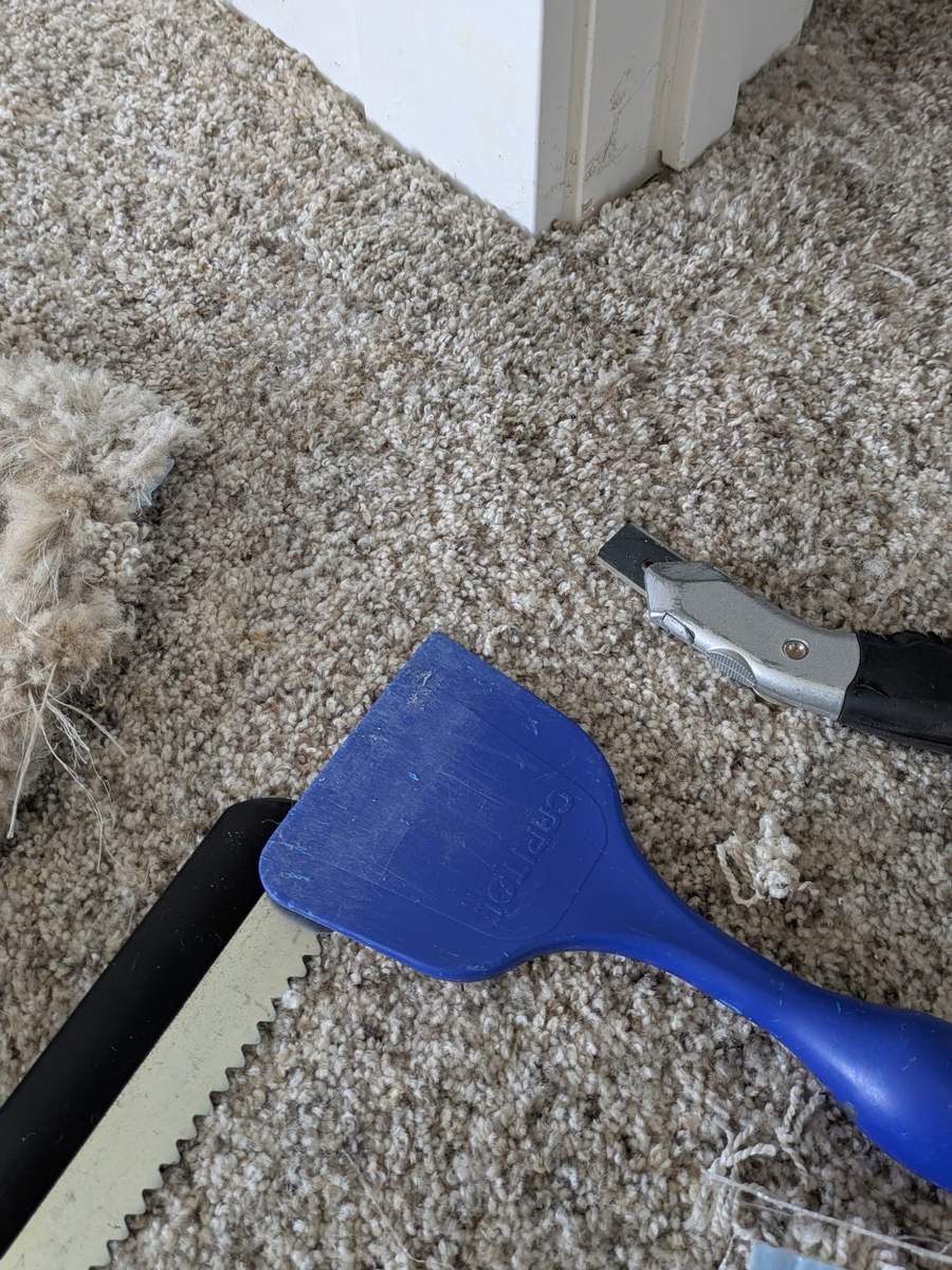 Carpet seam repair at a doorway with carpet repair tools