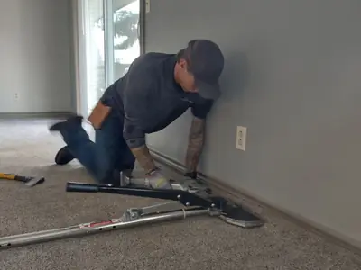 James re-stretching carpet along a wall with a power stretcher